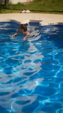 Bir kadın açık havuzda yüzüyor, güneşli bir günde rahatlık, ferahlık ve sükunetin tadını çıkarıyor.