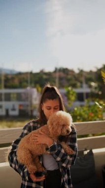Neşeli bir anda, parlak, güneşli bir günde tüylü köpeğini nazikçe kucaklayan genç bir kadın..