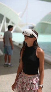 Modern bir şehir ortamında sanal gerçeklik deneyimi yaşayan genç bir kadın..