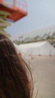Güneşli bir günde, uzun saçlı bir kadın modern bir mimari ortamda görüntüler yakalıyor, anın tadını çıkarıyor.