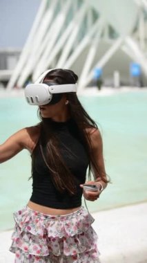 Genç bir kadın, havuzda kulaklığı ve çiçekli eteğiyle sanal gerçekliğin tadını çıkarıyor.