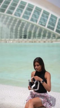 Kadın fütüristik bir ortamda VR kulaklığı deniyor. Güneşli bir günde modern teknolojinin ve engin deneyimlerin tadını çıkarıyor.