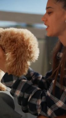 Ekose gömlekli bir kadın sevimli pofuduk köpeğiyle neşe içinde etkileşime girer, tatlı ve eğlenceli anları yakalar..