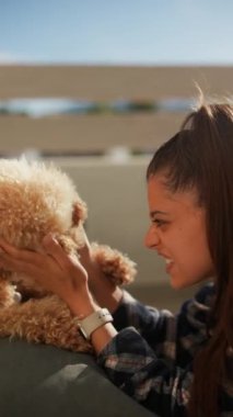 Mutlu genç bir kadın ve tüylü köpeği, dışarıda eğlenmenin tadını çıkarıyorlar, neşe ve şefkat dolu bir bağ yaratıyorlar.