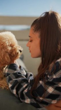 Bir kadın pofuduk köpeğiyle dışarıda eğleniyor, şefkatli anlarını paylaşıyor ve güneşli bir günde neşeli kucaklaşmalar yapıyor.