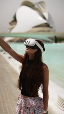 Çiçekli bir elbise giyen genç bir kadın, bir su merkezinin önünde sanal gerçeklik deneyiminin tadını çıkarıyor..