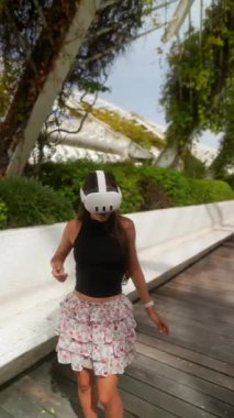 VR kulaklık takan bir kadın bahçeyi keşfediyor, bitkiler ve doğa arasındaki sanal gerçekliğin tadını çıkarıyor.