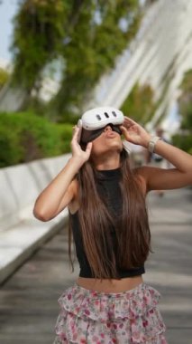 Uzun saçlı ve çiçekli etekli bir kadın güneşli bir günde sanal gerçekliğin tadını çıkarıyor..