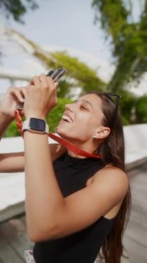 Genç bir kadın açık hava mimari sahasında, akıllı telefonuyla anılarını yakalıyor ve manzaranın tadını çıkarıyor.