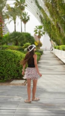 Genç bir kadın açık hava parkında sanal gerçeklik deneyiminin tadını çıkarırken VR kulaklık takıyor.