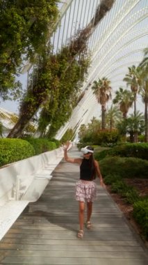 VR kulaklık takan bir kadın modern tasarımı olan yemyeşil bir serayı keşfediyor ve sanal bir deneyimin tadını çıkarıyor..