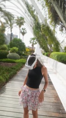 Sanal bir gerçeklikte, genç bir kadın yemyeşil ve palmiye ağaçlarında fütüristik bir ortam yaşıyor.