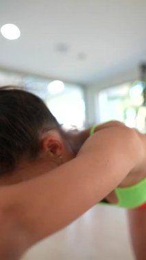 Neon yeşil bluzlu ve turuncu şortlu bir kadın spor salonunda spor yapıyor, spor ve sağlık konularına odaklanıyor..