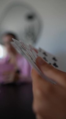 Arkadaşların evlerinde kağıt oynayarak eğlendikleri ve ellerinde kağıt oynadıkları yakın çekim görüntüsü.