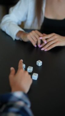 Bir grup insan masanın etrafında zar oyunundan zevk alıyor, nişanlarını sergiliyor ve eğleniyorlar.