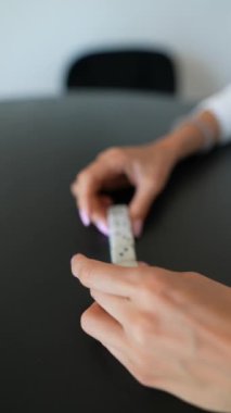 Yakın plan bir resim, zarları manipüle eden elleri gösterir ve kapalı bir masaya yerleştirilmiş bir tablette stilus kullanır.
