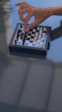 Yakın plan çekimler, açık havada, cam bir masada mini satranç oyununda el ele tutuşurken.