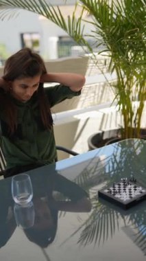 Açık havada satranç oynayan düşüncelere dalmış genç bir kız. Yansımaları ve yeşilliği modern estetik katıyor..