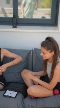 İki arkadaş, rahat ve rahat bir atmosferde rahat bir koltukta otururken dijital tablet kullanıyorlar.