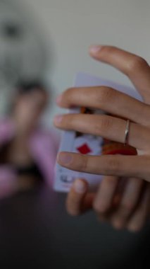 Eller yakın planda kalplerle ve kulüplerle kart numaraları yapıyor. Bulanık arkaplan sıradan sahneleri yakalar.