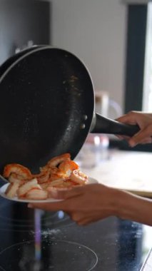 Bir şef, pişirilmiş karidesi tavadan tabağa dikkatlice aktararak karmaşık aşçılık becerilerini gösterir.