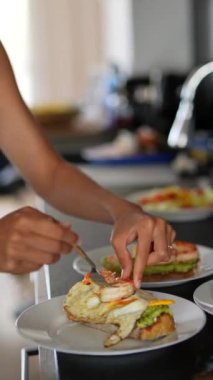 Modern bir mutfakta, bir insan taze avokado ve karidesli sandviç yapar, lezzetli bir yemek hazırlar.
