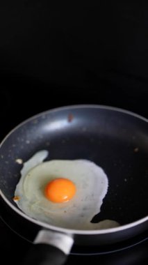 Yapışkan olmayan bir tavada kızaran tek bir yumurtanın yakın plan, minimal pişirme sahnesi..