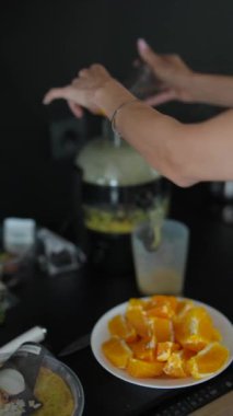 Dilimlenmiş portakallardan taze portakal suyu yapmak için meyve sıkacağı kullanan eller, mutfak tezgahı..