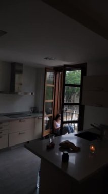 Modern mutfakta, açık bir kapı bir verandaya açılır, orada bir kişi akşam ışığı ve atmosferde dinlenir.