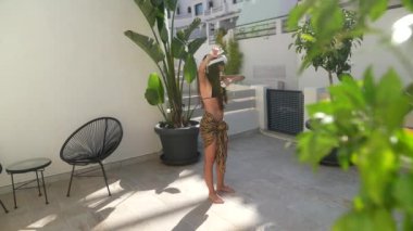 Güneşli bir günde, bir kadın çocuğuyla tropik bir bahçede oynarken bir bağ kurma anı yakalar.