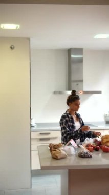 Bir kadın mutfak tezgahında taze yiyecekleri ayırıyor ve modern bir ortamda sağlıklı yemek pişirmeye hazırlanıyor.