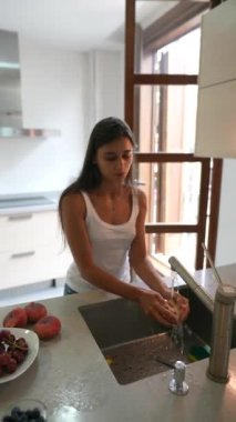 Modern mutfakta, temiz ve sağlıklı yiyecekleri taze ürünler ve doğal ışık ile hazırlayan bir kadın.