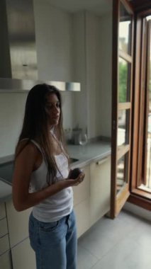 Modern bir mutfakta, huzurlu bir manzara ortaya çıkar. Genç bir kadın neşeyle bir avokado fırlatır. Huzur havası yayar.