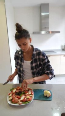 Günümüz mutfağında, bir kadın besleyici bir salata hazırlamak için çeşitli meyve ve sebzeleri dilimliyor.