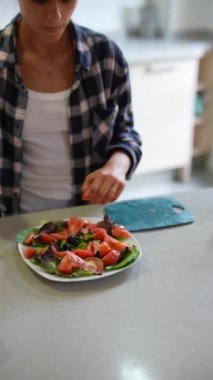 Modern bir mutfakta bir insan domatesli taze sebze salatası hazırlar, sağlıklı yemek ve beslenme üzerine odaklanır.