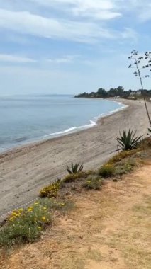 Sakin okyanus dalgaları, kumlu kıyıları olan sakin bir sahil sahili ve mavi gökyüzünün altındaki bir yol huzurlu bir manzara yaratır.