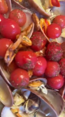 Taze midyeler ve baharatlarla süslenmiş canlı kırmızı domatesleri birleştiren lezzetli bir yemeğin yakın çekimi..