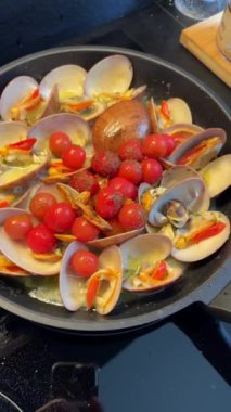 İçinde istiridye, kiraz domates, biber ve tavada sosis olan lezzetli bir deniz ürünleri tabağının yakın çekimi..