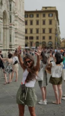 Canlı genç bir kadın neşeli bir şekilde Avrupa şehir simgesi önünde poz vererek değerli seyahat anılarını yakalıyor.