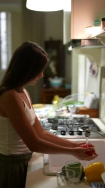 Modern bir mutfakta, bir kadın yemek pişirir, pencereden gelen doğal ışığı kullanarak, barışçıl ve düzenli bir yemek pişirme alanı yaratır.