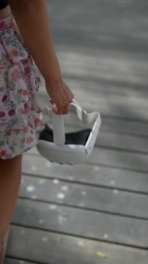 Açık hava ortamındaki bir kız beyaz bir VR kulaklık takıyor. Teknolojiyi, yeniliği ve keşfi simgeliyor.
