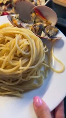 Beyaz tabakta spagetti, istiridye ve karışık sebze salatası. İtalyan aşıkları için mükemmel..