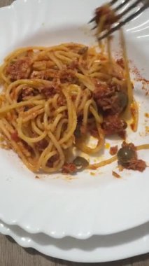 Peynir ve zeytinle süslenmiş beyaz bir tabakta servis edilen lezzetli bir bolonez spagettisinin yakın çekimi..