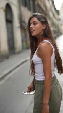 Uzun saçlı, beyaz bluzlu ve yeşil pantolonlu genç bir kadının profili..