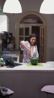 Modern bir mutfakta, bir kadın laptopun tarifine göre yemek yapar, odak noktası ve çağdaş mutfak teknikleri gösterir.