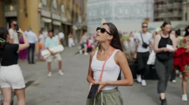 Telefonu olan bir kadın, popüler turistik yerlerin manzarası ve yaz atmosferiyle dolu bir şehri keşfediyor.