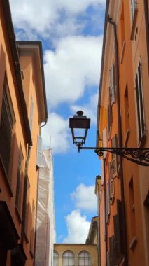 Parlak mavi gökyüzü ve tüylü beyaz bulutların altında klasik bir lamba direği olan Avrupa 'nın büyüleyici dar bir sokağı..