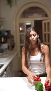 Genç bir kadın modern bir mutfakta mutlu bir şekilde yemek pişiriyor. Keyifli ve rahat görünüyor. Zamanının tadını çıkarıyor.