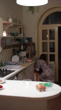 Bir kadın modern bir mutfakta, yumuşak ışıklandırmalı ve düzenli bir ortamda yemek hazırlıyor.