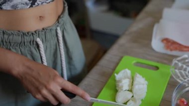 Mutfaktaki bir kesme tahtasında renkli sebzeleri dilimleyen biri iştah açıcı ve sağlıklı yemek hazırlığını gösteriyor.